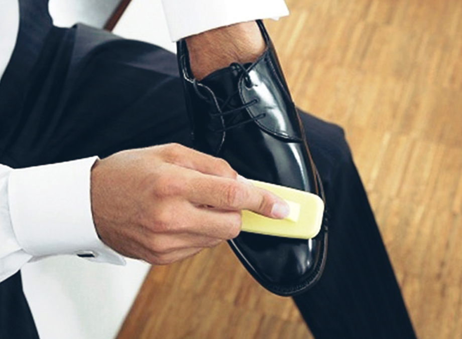 Homem limpando sapato de verniz com escova
