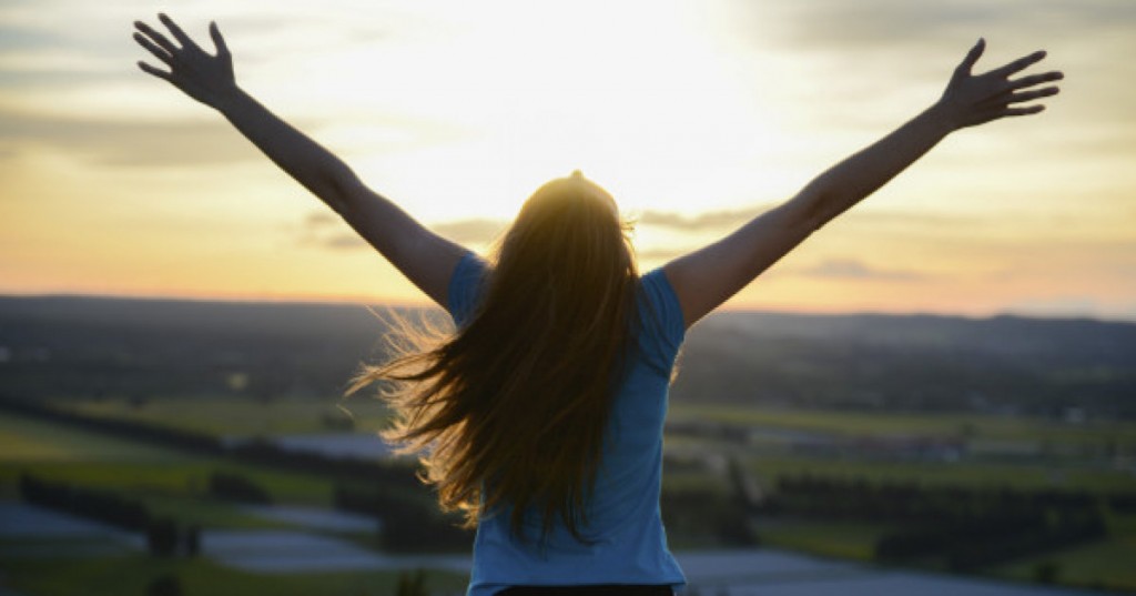 happy young woman outdoor rising hands and looking at landscape on sunset